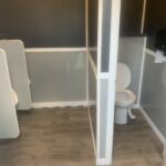 image displays the interior of a 6-station portable restroom trailer, designed for events or temporary needs